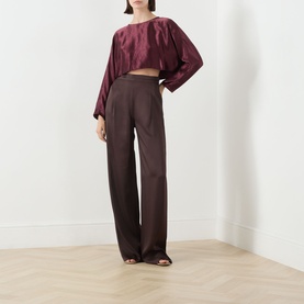 Model wearing Marella bordeaux acetate cropped shirt with wide sleeves, styled with dark wide-leg trousers and strappy heels.