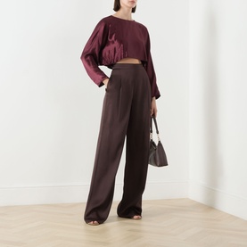Model wearing Marella bordeaux acetate cropped shirt with wide-leg trousers, carrying a dark structured handbag.