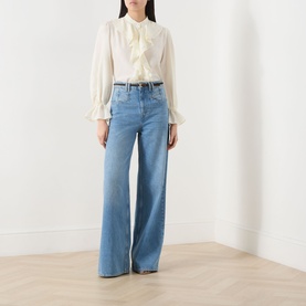 Model wearing Marella Caldaia Silk Ruffle Blouse in white with stand collar and puff sleeves, styled with wide-leg light blue jeans.