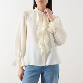 Model wearing Marella Caldaia Silk Ruffle Blouse in white with stand collar, front ruffle detail and puff sleeves, styled with blue jeans