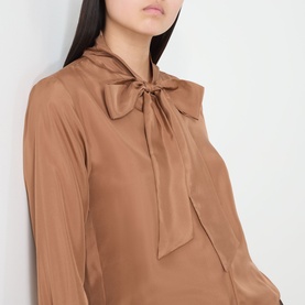 Model wearing Marella Kabala Silk Tie Front Blouse in Tobacco Brown, featuring a statement bow tie collar and long sleeves.