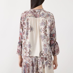 Model wearing Marella Girino Printed Blouse in cream, back view showing floral print, rear pleating, flared cuffs, styled with matching printed skirt.