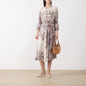 Model wearing Marella Girino Printed Blouse in cream with paisley print, styled with a midi skirt, tan bag and white mules.