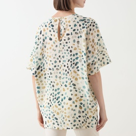 Model wearing Marella White Pebbles silk shirt, back view showing keyhole neckline and short flutter sleeves with multicoloured dot print.