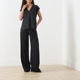 Model wearing Marella Brina Front-Pleat Blouse in black with V-neck and cap sleeves, styled with wide-leg black trousers.