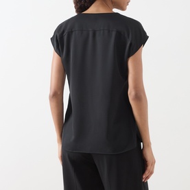 Model wearing Marella Brina Front-Pleat Blouse in black, shown from behind, with cap sleeves, smooth fabric and curved hem.