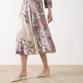 Model wearing Marella Decano Printed Skirt in cream, flared midi satin finish with paisley floral print, styled with cream kitten heel pumps.