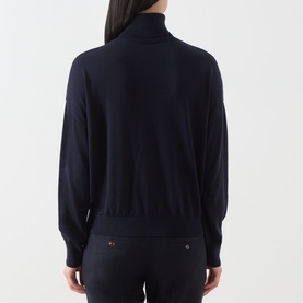 Model wearing Marella navy lyocell turtleneck jumper, rear view, styled with dark trousers with gold-tone button detail.