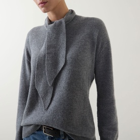 Model wearing Marella Giochi Tie-Neck Sweater in medium grey wool-cashmere with tie detail at neck and long sleeves, styled with blue jeans.
