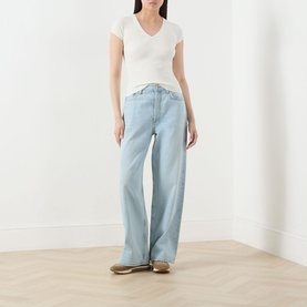 Model wearing Marella Vicario Rib-Knitted Sweater in white with V-neckline and short sleeves, styled with light-wash wide-leg jeans.