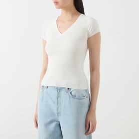 Model wearing Marella Vicario Rib-Knitted Sweater in white with V-neck and short sleeves, styled with light blue wide-leg jeans.