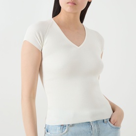 Model wearing Marella Vicario Rib-Knitted Sweater in white, V-neckline, short sleeves, rib-knit construction, styled with light blue jeans.