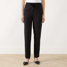 Model wearing Marella black tapered trousers with elasticated drawstring waist, styled with black bow-detail heels.