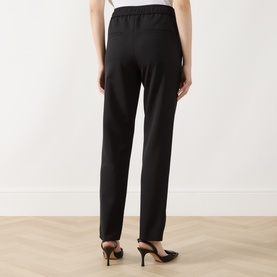 Model wearing Marella black straight-leg trousers with elasticated waist, styled with black kitten heel mules, rear view