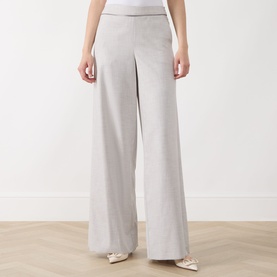 Model wearing Marella Pausa Wide-Leg Trousers in light grey with satin-trimmed waistband, wide-leg silhouette, styled with white heels.