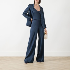 Model wearing Marella Aviation blue wide-leg trousers, styled with matching blazer, camisole top, and cream clutch bag.