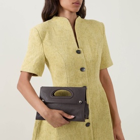 Model carrying Max&Co Caldaia Leather Book Bag in brown with silver-tone hardware, styled with a yellow short-sleeve dress.