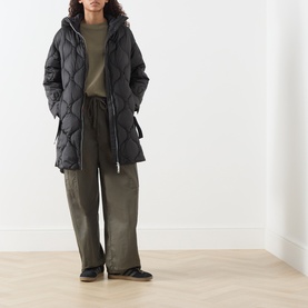 Model wearing Max&Co Vello Quilted Coat in black with onion quilting and high-neck hood, styled with khaki trousers and dark slip-on shoes