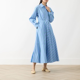 Model wearing Max&Co Ritmo Stripe Shirt Dress in light blue cotton with pointed collar, cinched waist and flared midi skirt. Styled with cream flats.