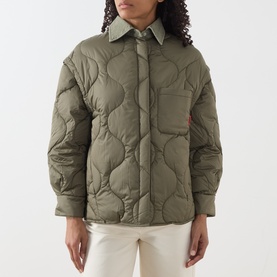 Model wearing khaki quilted shirt jacket with collar, chest pocket, and onion-stitch quilting, styled with cream trousers