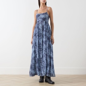 Model wearing Max&Co light blue snake-print maxi dress with spaghetti straps, tiered skirt, styled with black ankle boots