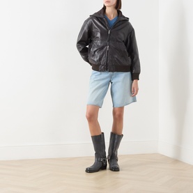 Model wearing Max&Co dark brown leather jacket with hood, styled with light blue denim shorts and black knee-high boots