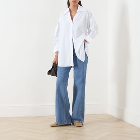 Model wearing Max&Co Colle Poplin Shirt in white with wide-leg blue jeans, styled with beige loafers and a black clutch bag.