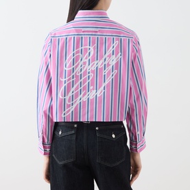 Model wearing Max&Co pink pinstripe cropped cotton shirt, back view showing cursive logo graphic, styled with dark indigo jeans.