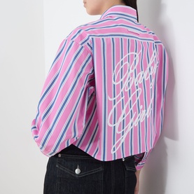 Model wearing Max&Co pink pinstripe cotton shirt, back view, with cursive logo detail. Styled with dark denim jeans.