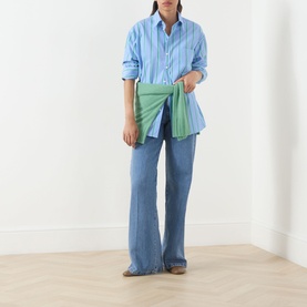 Model wearing Max&Co Dama Stripe Shirt in light blue, styled with wide-leg jeans and carrying a green pleated clutch bag.