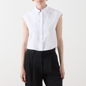 Model wearing Max&Co optical white cotton sleeveless shirt with pintuck bib front, dark button detail, styled with black tailored trousers