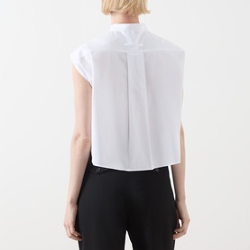 Model wearing Max&Co optical white cotton shirt, back view showing pleat detail and cap sleeves, styled with black trousers