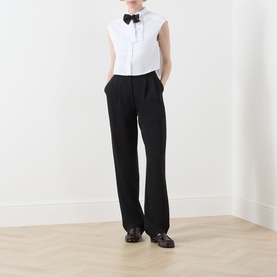 Model wearing Max&Co optical white sleeveless cotton shirt with bow detail, styled with black wide-leg trousers and dark loafers.