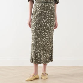 Model wearing Max&Co Agenda Printed Skirt in kaki print floral jacquard, midi length bias cut silhouette, styled with yellow mule flats