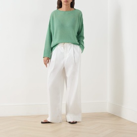 Model wearing Max&Co Stampa Knit Sweater in green plain with white wide-leg drawstring trousers and dark flat sandals.