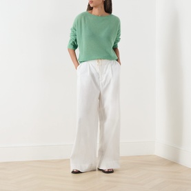 Model wearing Max&Co Stampa Knit Sweater in green plain with white wide-leg trousers and brown shoes