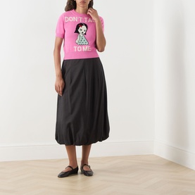 Model wearing Max&Co Argento Graphic Knit Top in pink jacquard with intarsia doll graphic, styled with black midi balloon skirt and flat shoes.