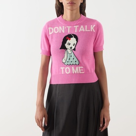 Model wearing Max&Co Argento Graphic Knit Top in pink jacquard with "Don't Talk To Me" doll intarsia, styled with black midi skirt