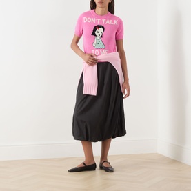 Model wearing Max&Co Argento Graphic Knit Top in pink jacquard with "Don't Talk To Me" slogan, styled with black midi skirt and ballet flats