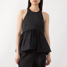 Model wearing Max&Co Pietre Peplum Top in black satin with halter neckline, sleeveless cut and gathered balloon-hem peplum detail