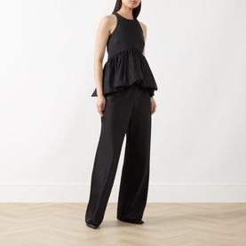 Model wearing Max&Co Pietre Peplum Top in black satin with balloon hem, styled with wide-leg black trousers