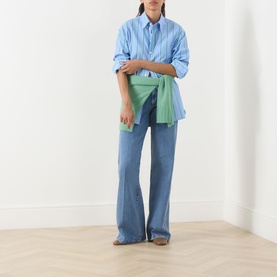 Model wearing Max&Co Liriche Mid-Rise Wide Leg Jeans in navy, styled with a blue striped shirt and green clutch bag.