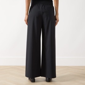 Model wearing Max&Co Orche Technical Straight Leg Trousers in black, elasticated waistband, wide-leg fit, styled with black top and heeled shoes.