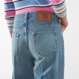 Model wearing Max&Co navy denim jeans with branded leather back patch, styled with a multicolour striped knit top. 100% cotton.