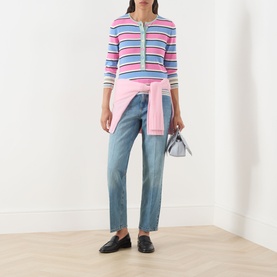 Model wearing Max&Co navy denim straight-leg trousers, styled with a pink striped knit top and black loafers, carrying a mini bag.