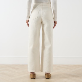 Model wearing Max&Co milk wide-leg cotton trousers, rear view, styled with a white ribbed top and tan clogs.