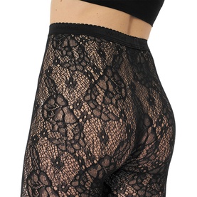 Model wearing Wolford black floral lace tights with elasticated waistband, close-up detail shot showing sheer patterned design