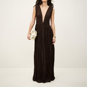 Model wearing Bash Tania Pleated Dress in brown, deep V-neck, metal jewel waist detail, maxi length. Styled with a gold clutch bag.