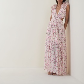 Model wearing Anne Louise Boutique pink floral maxi dress with deep V-neck, ruffle trim, cutout waist detail, and tiered skirt