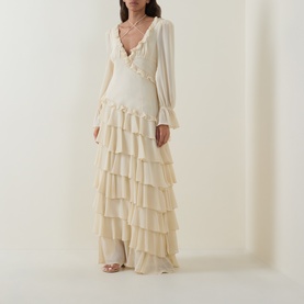 Model wearing Anne Louise Boutique cream maxi dress with tiered ruffle skirt, long balloon sleeves and V-neckline with frill trim